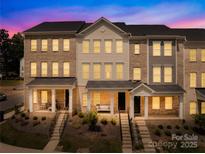 Charming townhome exterior with brick facade, covered porch, and well-manicured landscaping at dusk at 13920 Winmau Ln, Huntersville, NC 28078