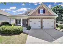Charming home featuring stone accents, shingle details, an attached two-car garage and manicured landscaping at 15120 Cavanshire Trl, Charlotte, NC 28278