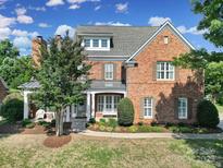 Beautiful brick home with manicured lawn, covered porch and a lush tree providing shade at 2909 Julian Glen Cir, Waxhaw, NC 28173