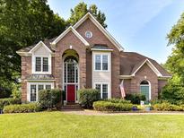 Stunning brick home with a red door, mature landscaping and a manicured lawn creates exceptional curb appeal at 3401 Cresta Ct, Charlotte, NC 28269