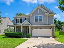 Charming two-story home with a well-manicured lawn and a two-car garage on a sunny day at 10409 Dominion Village Dr, Charlotte, NC 28269