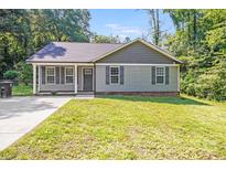 Charming single-story home with gray siding, shutters, manicured lawn, and a well-lit concrete driveway at 115 Dove Sw Ave, Concord, NC 28025