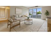 Bright living room features a sliding glass door, modern decor, and lots of natural light at 1300 Reece Rd # 305, Charlotte, NC 28209