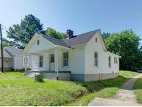 Quaint white home featuring black roof, chimney, and a cozy covered front porch area at 2414 Lane St, Kannapolis, NC 28083