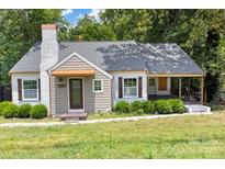 Charming bungalow-style home with brick chimney, covered front porch, and mature landscaping at 308 Davis Park Rd, Gastonia, NC 28052