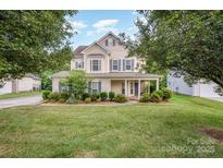 Charming two-story home featuring a covered front porch and manicured lawn at 7731 Sedgebrook E Dr, Stanley, NC 28164