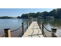 Long wooden dock with black rope railings extending out onto a peaceful lake, with calm waters and wooded shores in the background at 126 Aqua Dr, Mooresville, NC 28117
