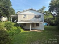 Two-story home featuring a covered front porch and attached carport, set on a lawn with mature trees at 2103 Clawson Ave, Kannapolis, NC 28081