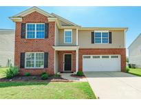 Charming two-story home featuring a brick facade, attached garage, and well-maintained front lawn at 2357 Riding Trail Rd, Gastonia, NC 28054