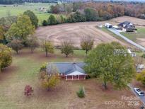 Expansive aerial view of the charming brick home and the surrounding acreage and fall foliage at 3113 Old Pageland Marshville Rd, Wingate, NC 28174