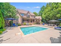 A luxury brick home showcases its beautiful pool and lounge area, perfect for outdoor relaxation and entertainment at 600 Beauhaven Ln, Waxhaw, NC 28173