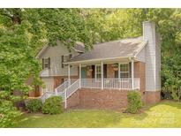 Charming two-story home with gray siding, brick accents, a welcoming front porch, and mature trees providing shade at 6418 Tivoli Ct, Charlotte, NC 28211