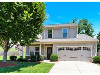 Charming home featuring gray siding, a two-car garage, manicured lawn, and beautiful mature trees at 7339 Dover Mill Sw Dr, Concord, NC 28025
