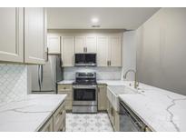Bright kitchen with stainless steel appliances, patterned backsplash, white cabinetry, and marble countertops at 795 Peninsula Dr, Davidson, NC 28036