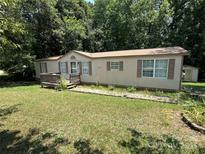 Tan single-story home with a small deck, brown shutters and a large front yard at 1355 Oak Breeze Dr, Mooresville, NC 28115