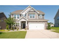 Charming two-story home with a stone facade, a manicured lawn and an attached two-car garage on a sunny day at 17718 Terryglass Ln, Charlotte, NC 28278