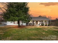 Charming home with covered front porch, decorative columns and metal roof on a large lot at sunset at 24253 Old Aquadale Rd, Albemarle, NC 28001