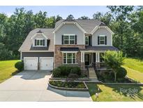 Charming two-story home featuring stone and gray siding, a well-manicured lawn, and a two-car garage at 2525 Surveyor General Dr, Waxhaw, NC 28173