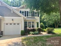 Charming home boasts a manicured lawn, attached garage, and inviting covered porch, complemented by lush landscaping at 2545 Chasewater Dr, Fort Mill, SC 29707