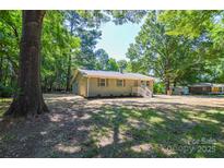 Lovely one-story brick home, surrounded by mature trees, and landscaped for attractive curb appeal at 402 Gibson Park Dr, Huntersville, NC 28078