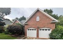 Red brick home featuring a two-car garage with white doors and mature landscaping at 1344 Moonshadow Ln, Shelby, NC 28150