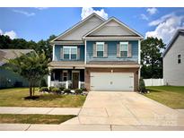 Charming two-story home with a well-manicured lawn, a two-car garage, and a welcoming front porch at 243 Kerri Dawn Ln, Locust, NC 28097