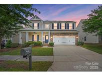 Charming two-story home with a covered front porch, stone accents, and an attached two-car garage at 3020 Fallondale Rd, Waxhaw, NC 28173