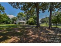 Charming two-story home with a lovely lawn and gravel driveway, framed by mature shade trees at 1239 Mac Ln, Stanley, NC 28164