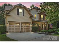 Charming home featuring a manicured lawn, a two-car garage, and a stone-accented porch at 1800 Robbins Meadows Dr, Waxhaw, NC 28173