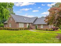 Charming brick home featuring a well-manicured lawn, mature trees, and a classic architectural design at 36433 Azalea Cir, New London, NC 28127