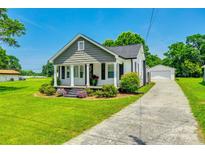 Charming home boasts a landscaped front yard and a detached garage with a long driveway on a sunny day at 903 Rhode Island Ave, Kannapolis, NC 28083