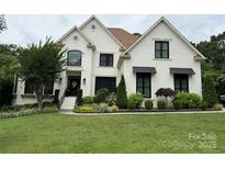 Stunning white brick home boasts lush landscaping, a manicured lawn, and black window accents at 9604 Oliver Ct, Harrisburg, NC 28075
