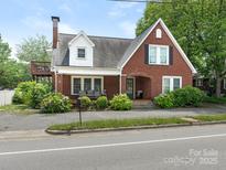 Charming brick home featuring an upstairs deck, a cozy front porch, and lovely garden landscaping at 1102 Lane St, Kannapolis, NC 28083