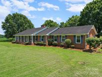 Charming brick home with a lush green lawn, blue shutters and mature landscaping at 1904 Old Peachland Rd, Marshville, NC 28103