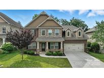 Beautiful two-story home featuring a well-manicured lawn, brick and stone accents, and an attached two-car garage at 2377 Maple Grove Nw Ln, Concord, NC 28027