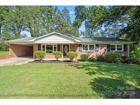 Charming brick home with a well-manicured lawn and mature trees creating a welcoming curb appeal at 4322 Greenhaven Ln, Gastonia, NC 28056