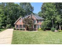 Charming two-story brick home featuring mature trees, manicured lawn, and black shutters at 5051 Carillon Way, Charlotte, NC 28270