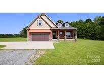 Charming craftsman-style home with a covered front porch, two-car garage, and a well-maintained lawn at 670 Cricket Ln, Mt Ulla, NC 28125