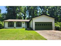 Charming single-story home featuring white siding, green shutters, and a well-manicured lawn with mature trees at 7228 Rollingridge Dr, Charlotte, NC 28211