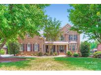 Traditional brick home with manicured front lawn and mature trees, featuring a covered front porch at 844 Clonmel Dr, Matthews, NC 28104