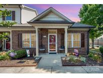 Charming brick home featuring a covered front entrance, beautiful landscaping, and outdoor seating area at 2773 Clover Nw Rd, Concord, NC 28027