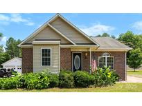 Charming brick home with a well-manicured lawn, complemented by lush landscaping around the front entrance at 400 N Main Gq St, Granite Quarry, NC 28146