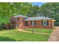 Charming brick home with a well-manicured lawn, black shutters, and mature trees at 1008 Dumbarton Rd, Gastonia, NC 28054