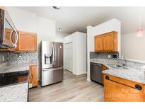 Bright kitchen featuring stainless steel appliances, wood cabinets, granite countertops, and mosaic backsplash at 11411 Ridge Oak Dr, Charlotte, NC 28273