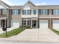 Charming townhome featuring stone accents, brown shutters, and a well-manicured front yard with flower beds at 342 Battery Cir, Clover, SC 29710