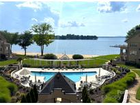 Beautiful lakefront pool area with beach, clear water, lounge seating, and lovely landscaping at 633 Portside Dr, Davidson, NC 28036