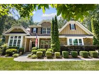 Charming brick home featuring manicured landscaping, an American flag, and a welcoming entrance at 7327 Snowbird Ct, Mint Hill, NC 28227