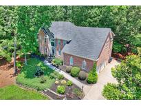 Impressive brick home with manicured landscaping, fountain, and three-car garage nestled in lush greenery at 19900 Stough Farm Rd, Cornelius, NC 28031