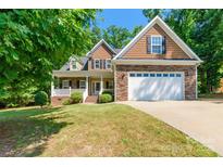 Inviting two-story home showcasing a blend of stone and wood siding, complemented by a well-manicured lawn at 4203 Flint Dr, Lancaster, SC 29720