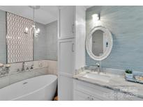 Bright bathroom features a soaking tub, patterned tile accent wall, and white vanity with a decorative mirror at 666 Tryon Pl, Gastonia, NC 28054
